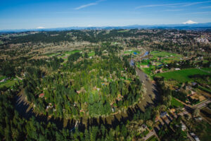 Aerial image of the Tualatin River curving around residential houses. Mt Hood and Mt St Helens sit in the background.