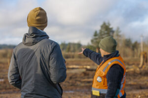A Clean water services employee points to a project site while talking to a community member.