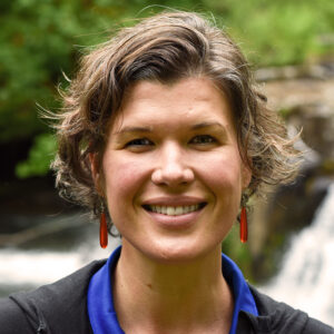 Headshot of person with blue and black shirt with a waterfall in the background. Person is Julie Cortez.
