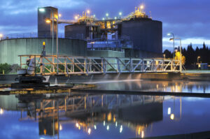 Clean Water Services Water Resource Recovery Facility in Rock Creek, Oregon. Shown at dusk with bright lights illuminating a large clarifier on site.