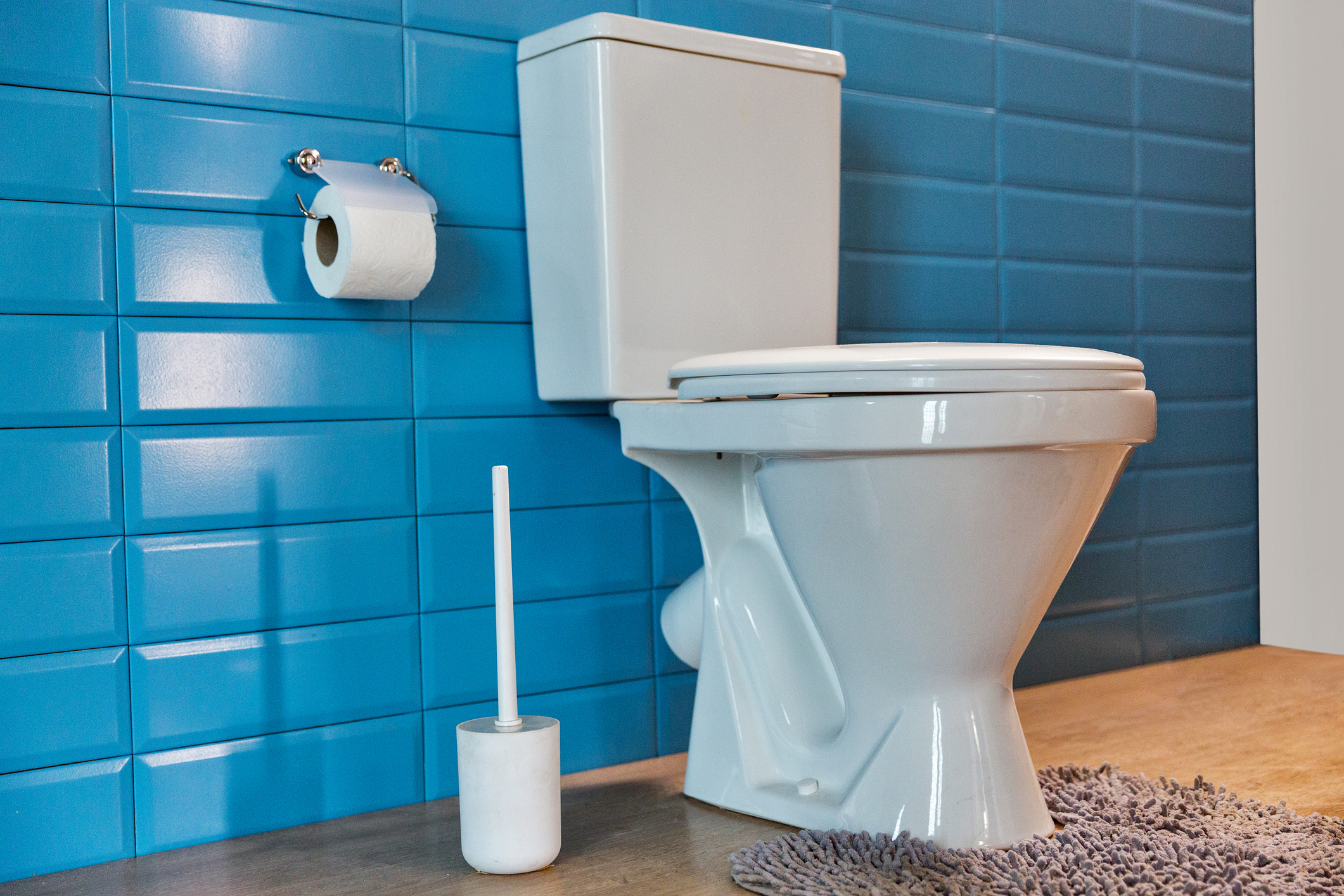 A white toilet against a blue tile wall.