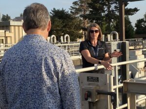 A CWS employee shares information about Durham Water Resource Recovery Facility outside over pools of water being treated.