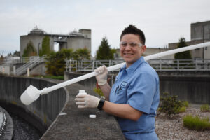 A CWS employee holds a long poll with a cup at the end used to collect samples for water quality testing.