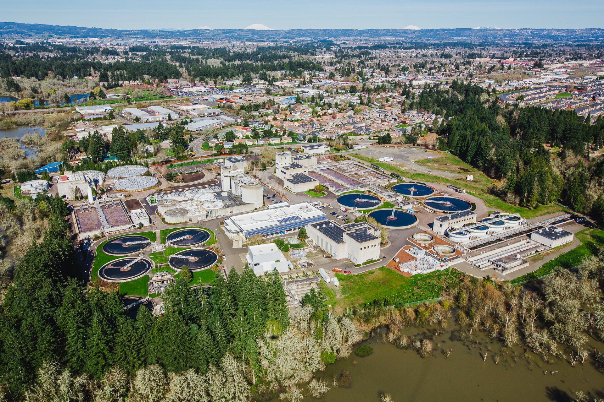 Imagen aérea de la Instalación de Recuperación de Recursos Hídricos de Rock Creek de Clean Water Services, con vista a las montañas al fondo y Rock Creek —un afluente principal del río Tualatin— en primer plano.